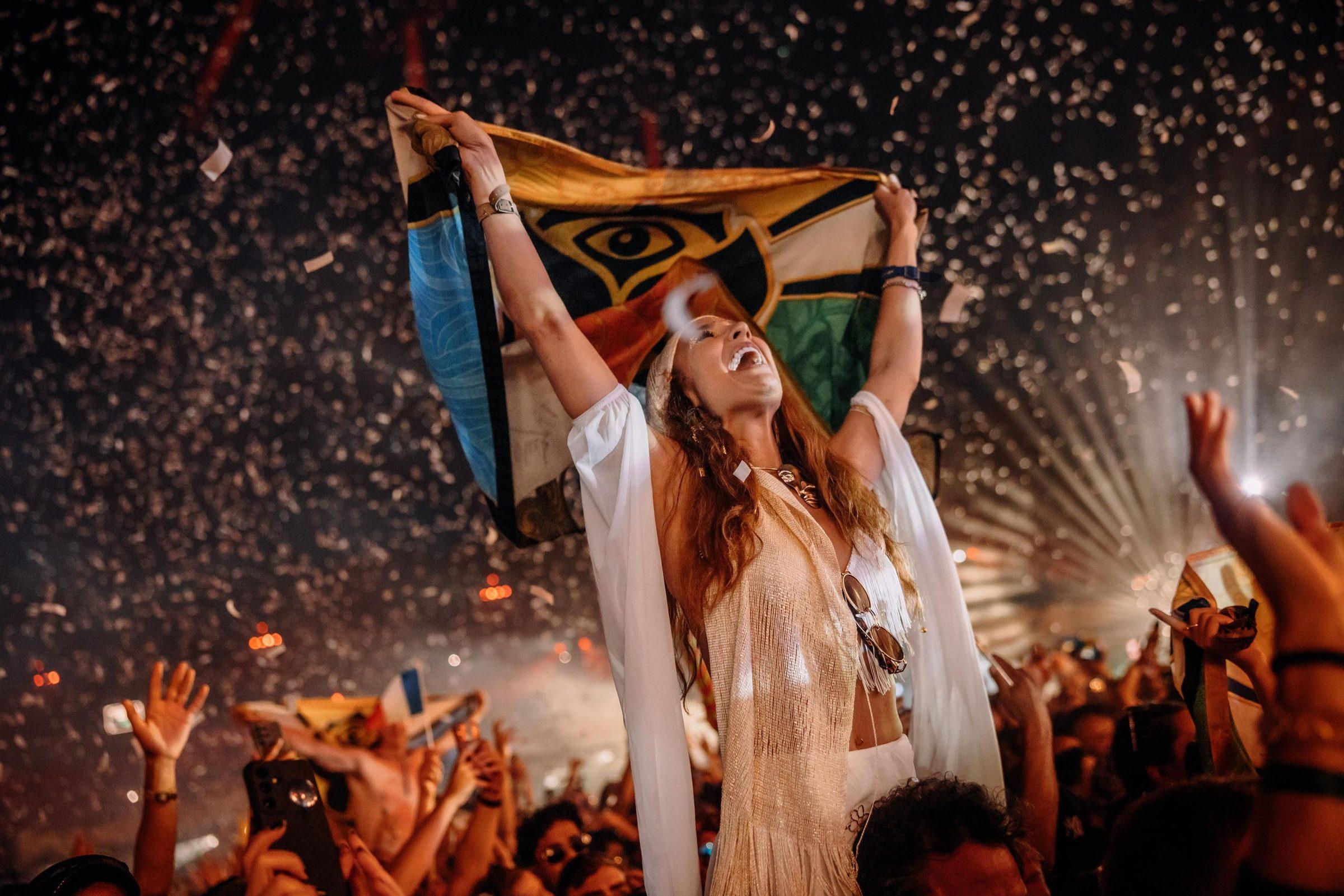 Fã celebrando com a bandeira do Tomorrowland sob chuva de confete